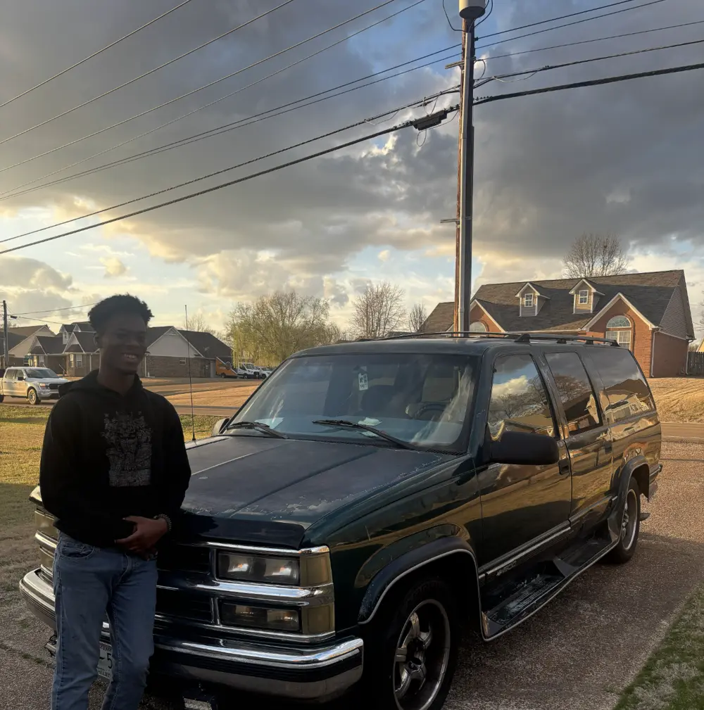 Quinton beside Ivy, his Chevrolet Suburban